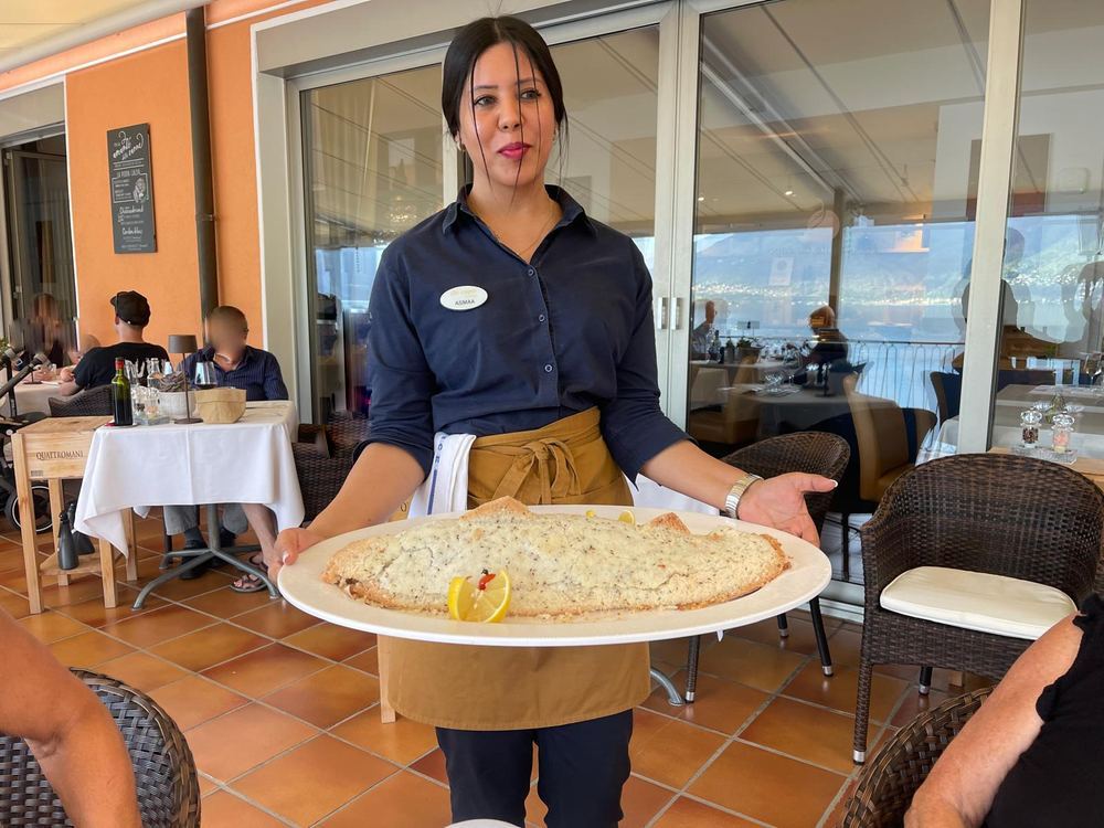Service präsentiert frisch gebackenen Fisch auf der Seeterrasse des Ristorante da capo